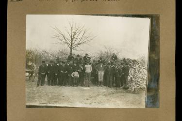 crowd of people posing for photo during a spraying demonstration; middle row depicts Black men in attendance