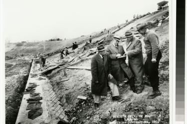 H.C. Byrd talking to white men while Black men in the background are at work on Byrd Stadium construction, January 16th, 1950 