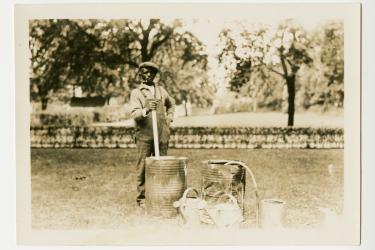 Black man standing with barrels and watering cans