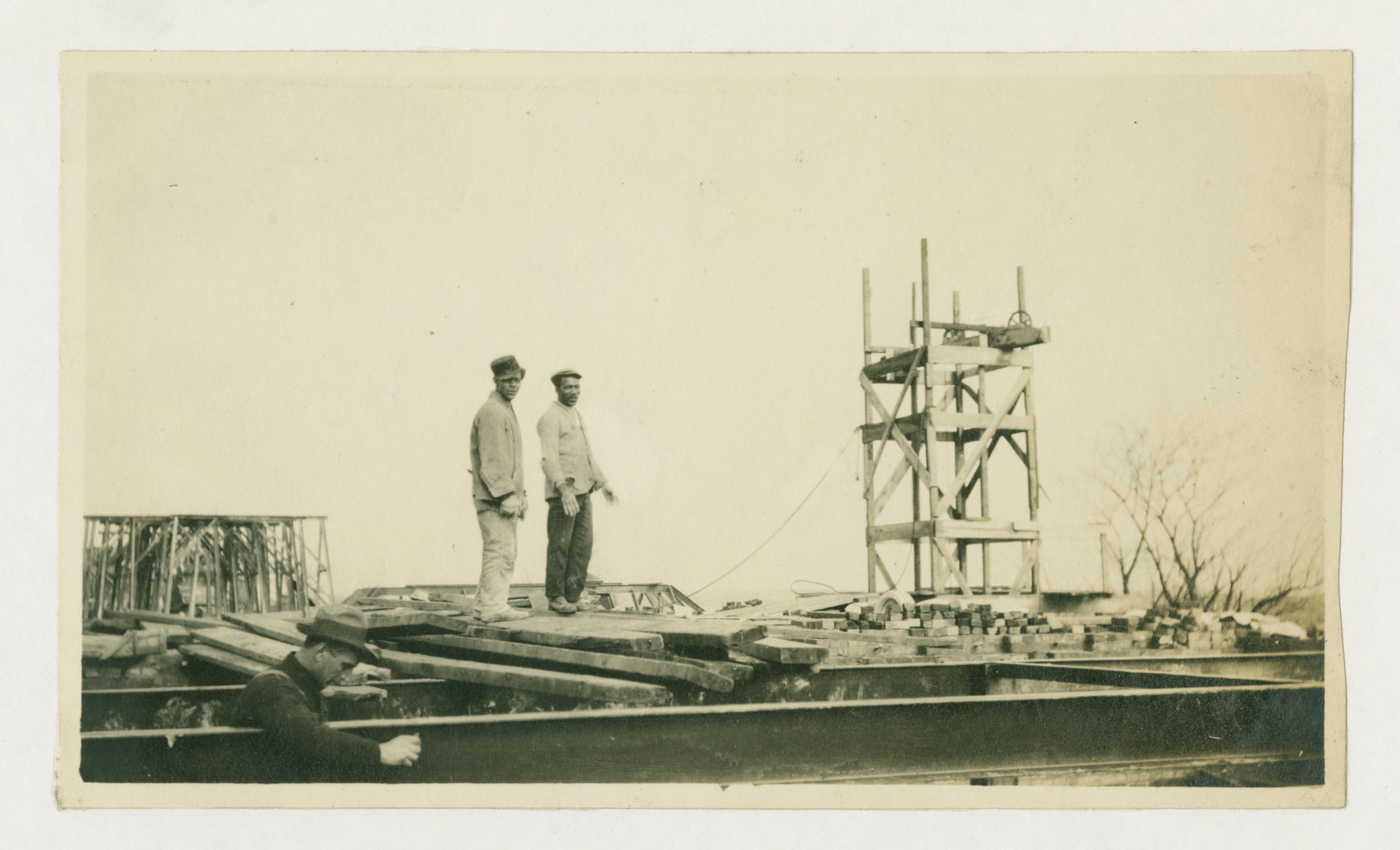 two Black men standing atop Calvert Hall during construction c. 1916