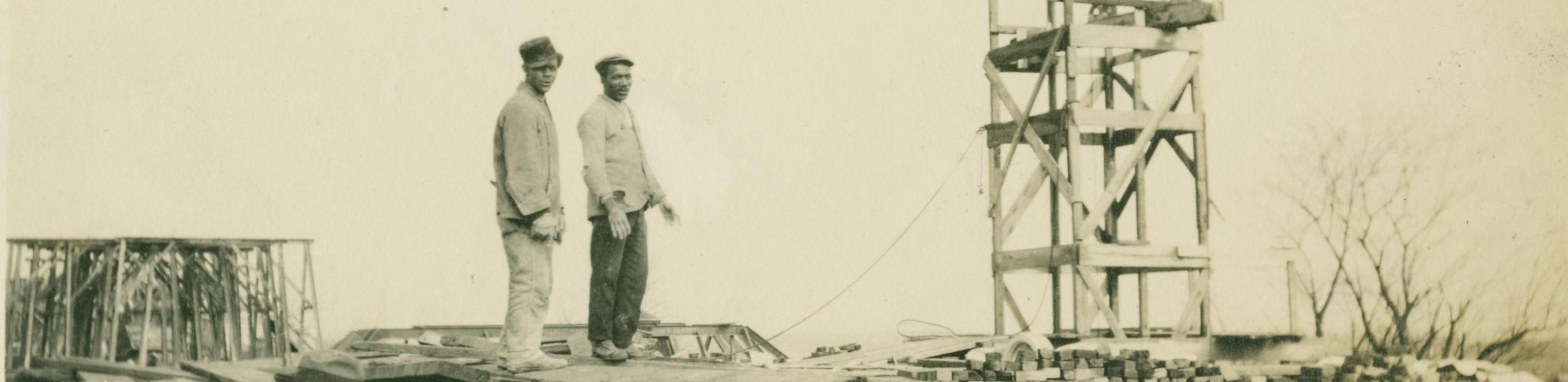 two Black men standing atop Calvert Hall during construction c. 1916