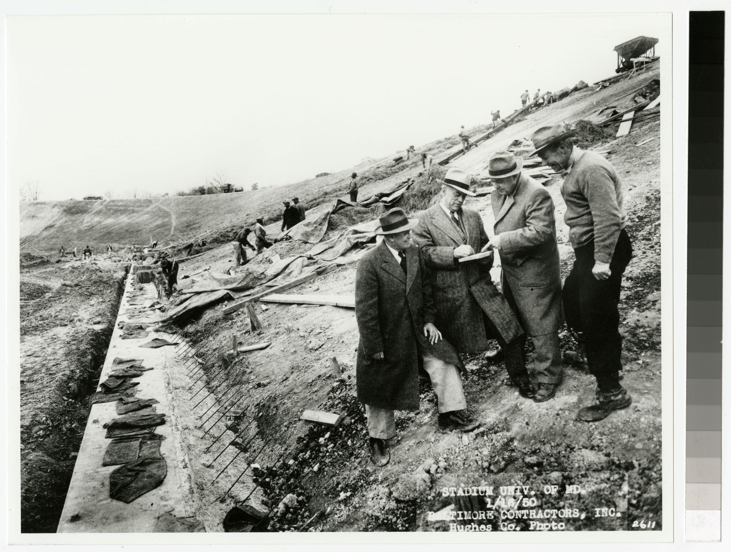 H.C. Byrd talking to white men while Black men in the background are at work on Byrd Stadium construction, January 16th, 1950 