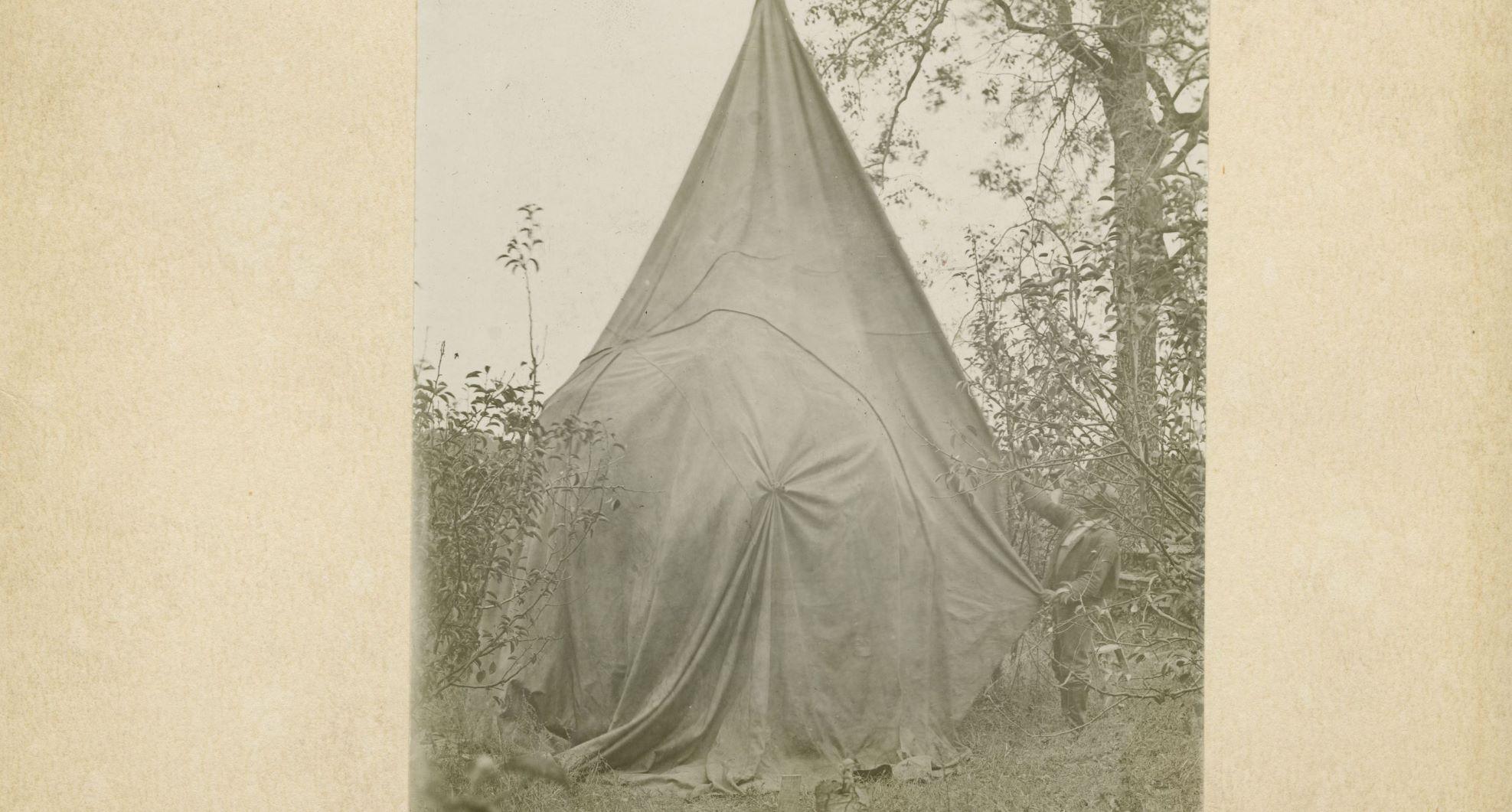 Black man putting sheet tent over a tree