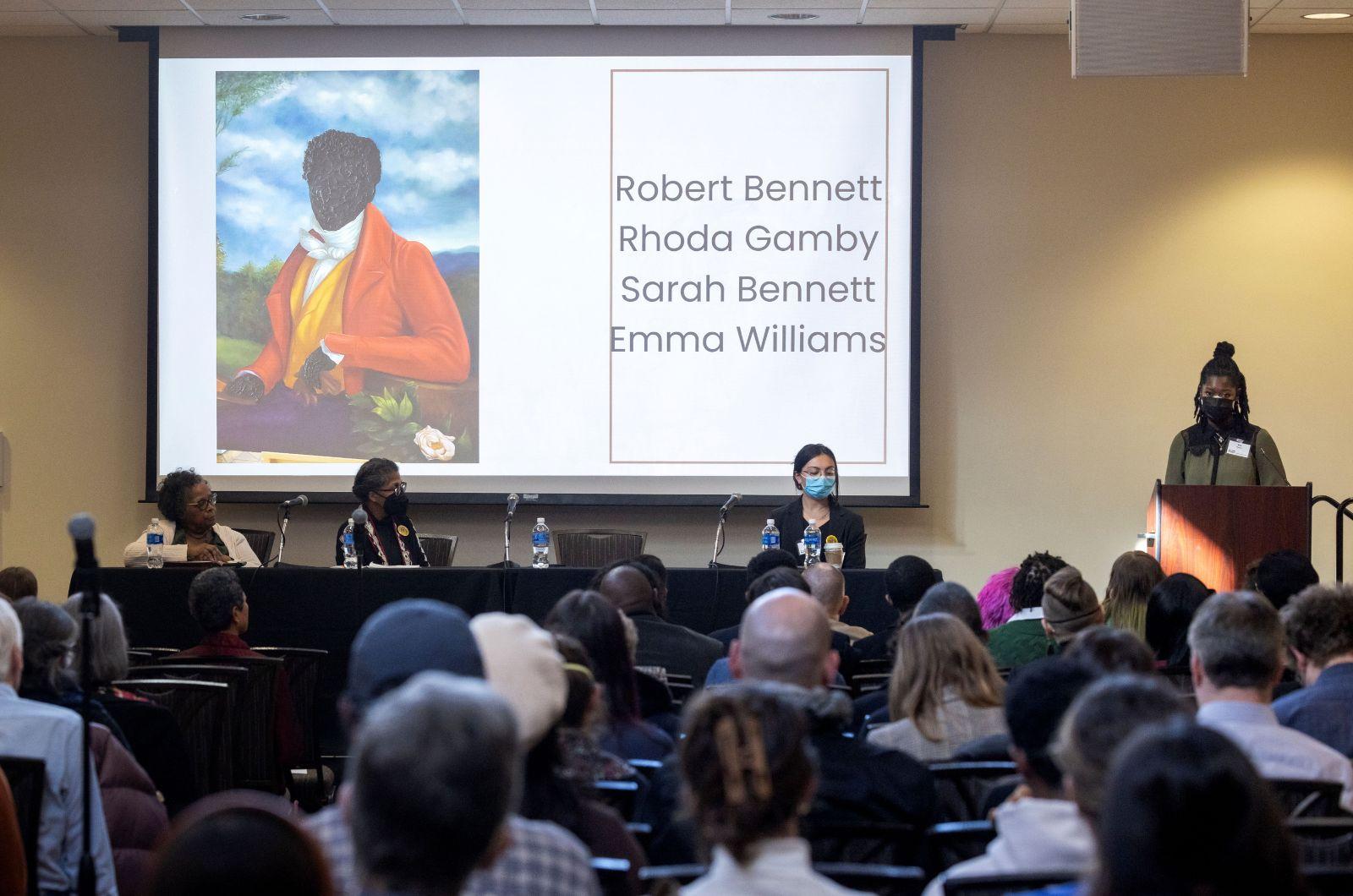 Mia Moore standing at a podium in front of her presentation